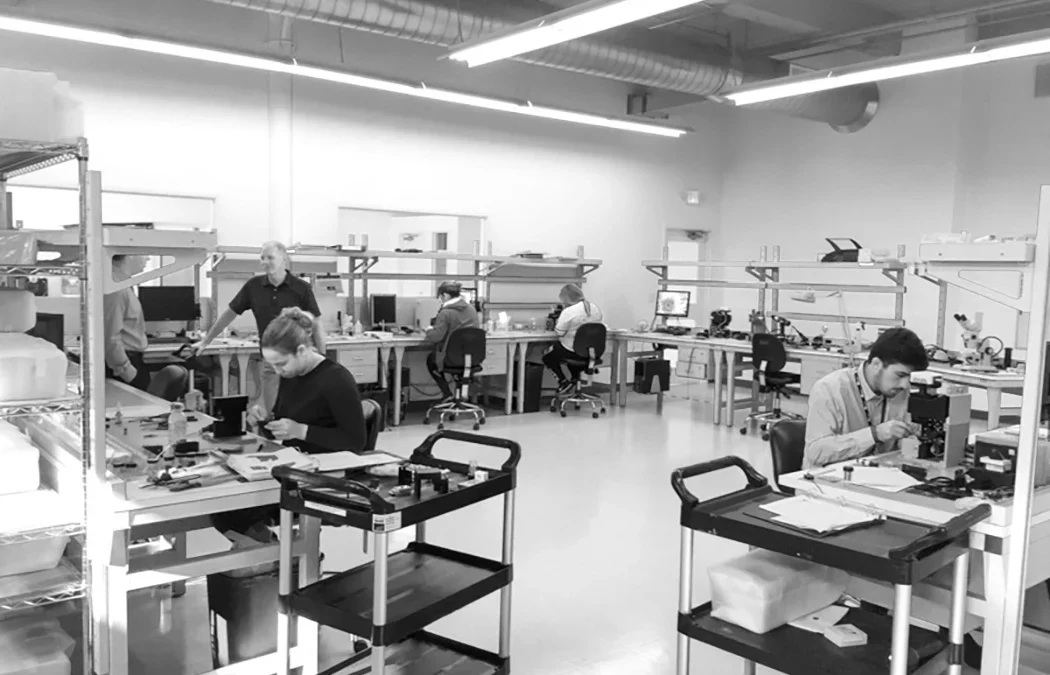 Production staff working at industrial workstations on a manufacturing floor.